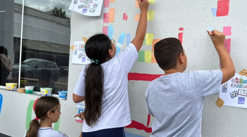 Estudantes pintam desenhos na fachada da Biblioteca Municipal